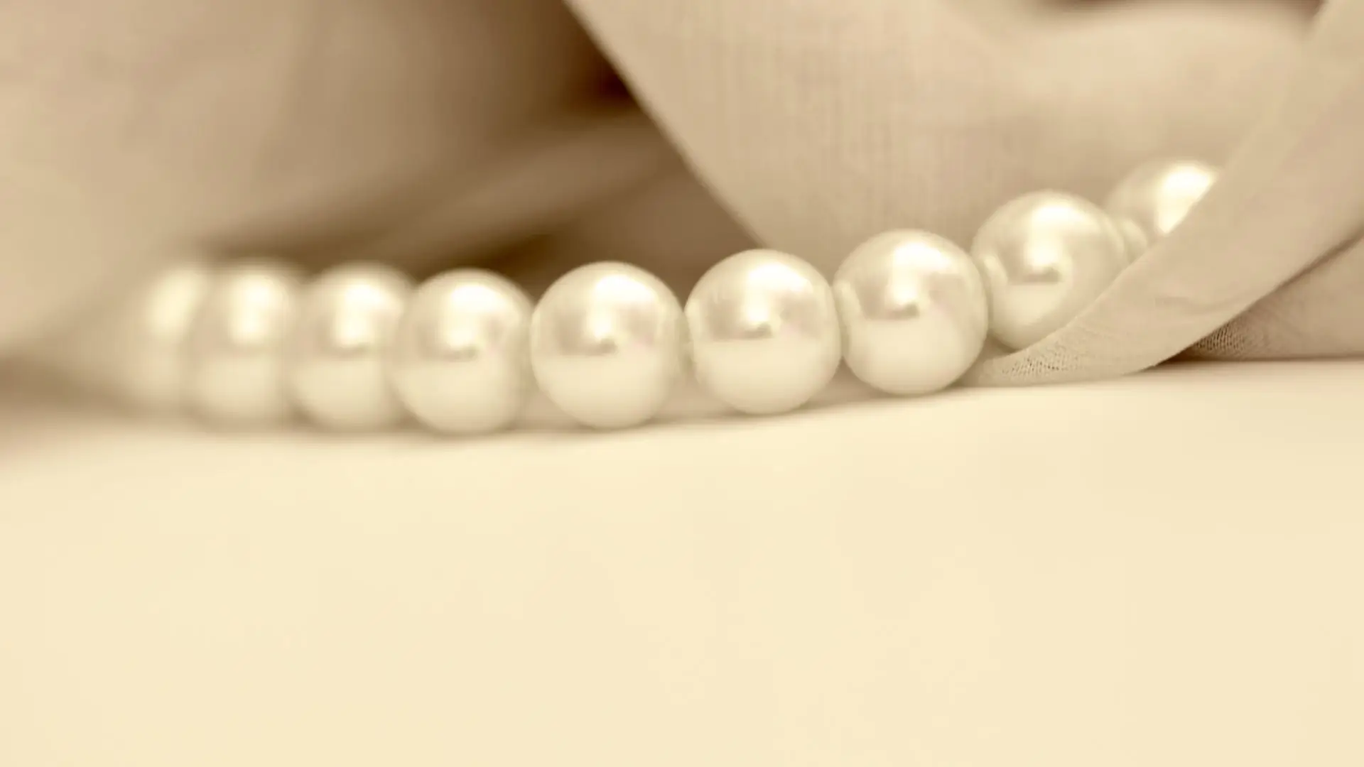 A close-up shot of a classic pearl necklace set against a bright white backdrop.