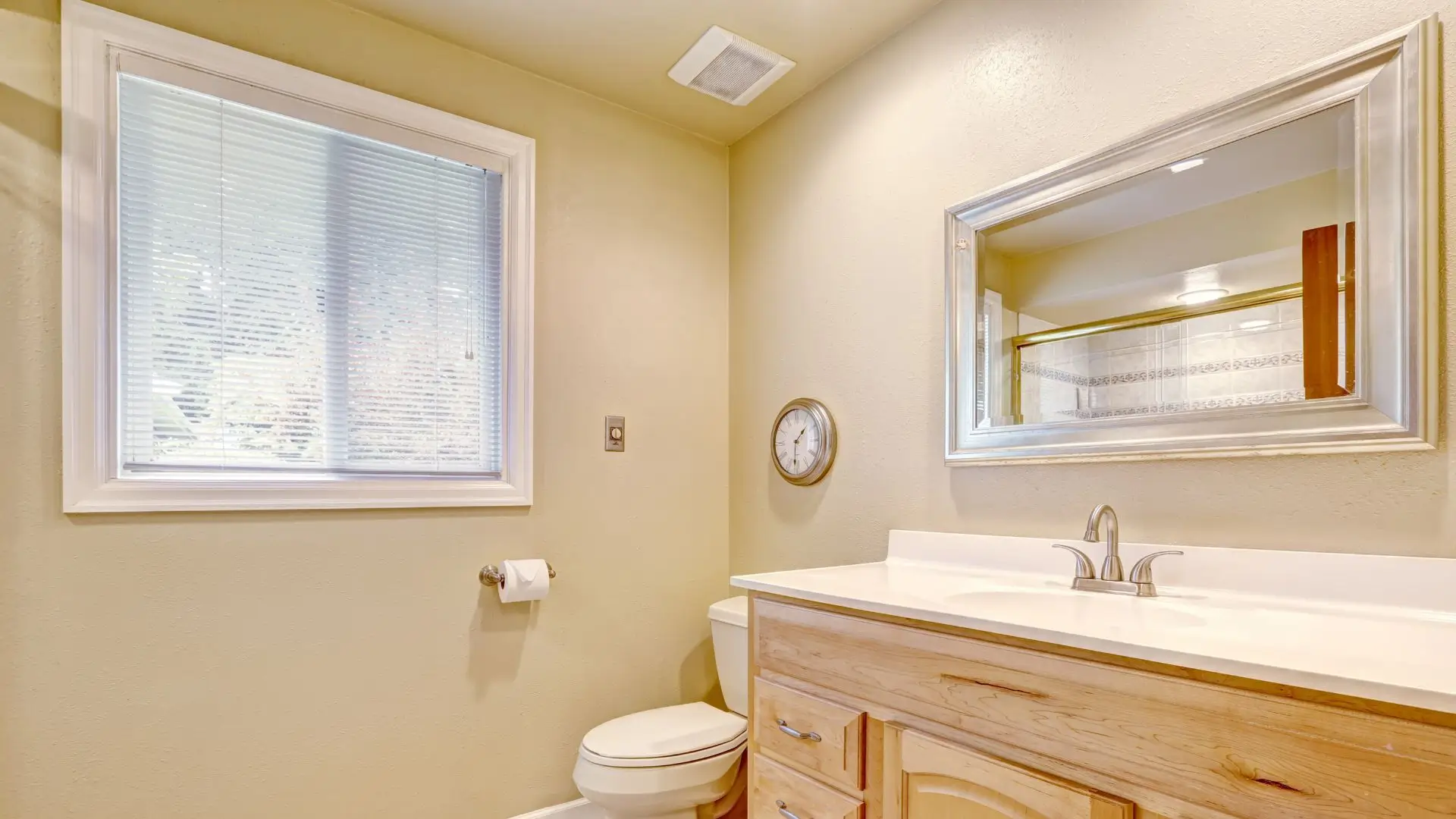 A clean bathroom featuring a sink, toilet, and a large mirror reflecting the space.