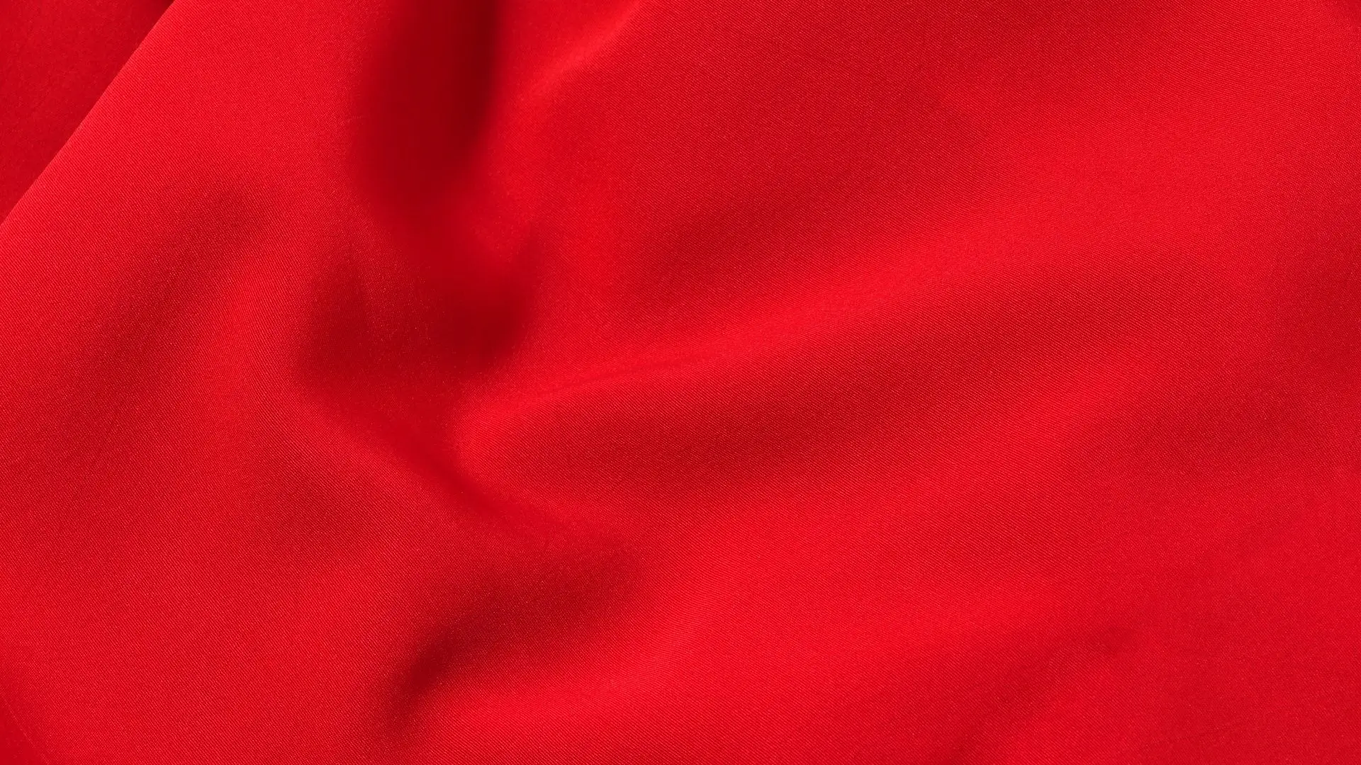 Close-up view of luxurious red silk fabric, showcasing its smooth texture and vibrant color.