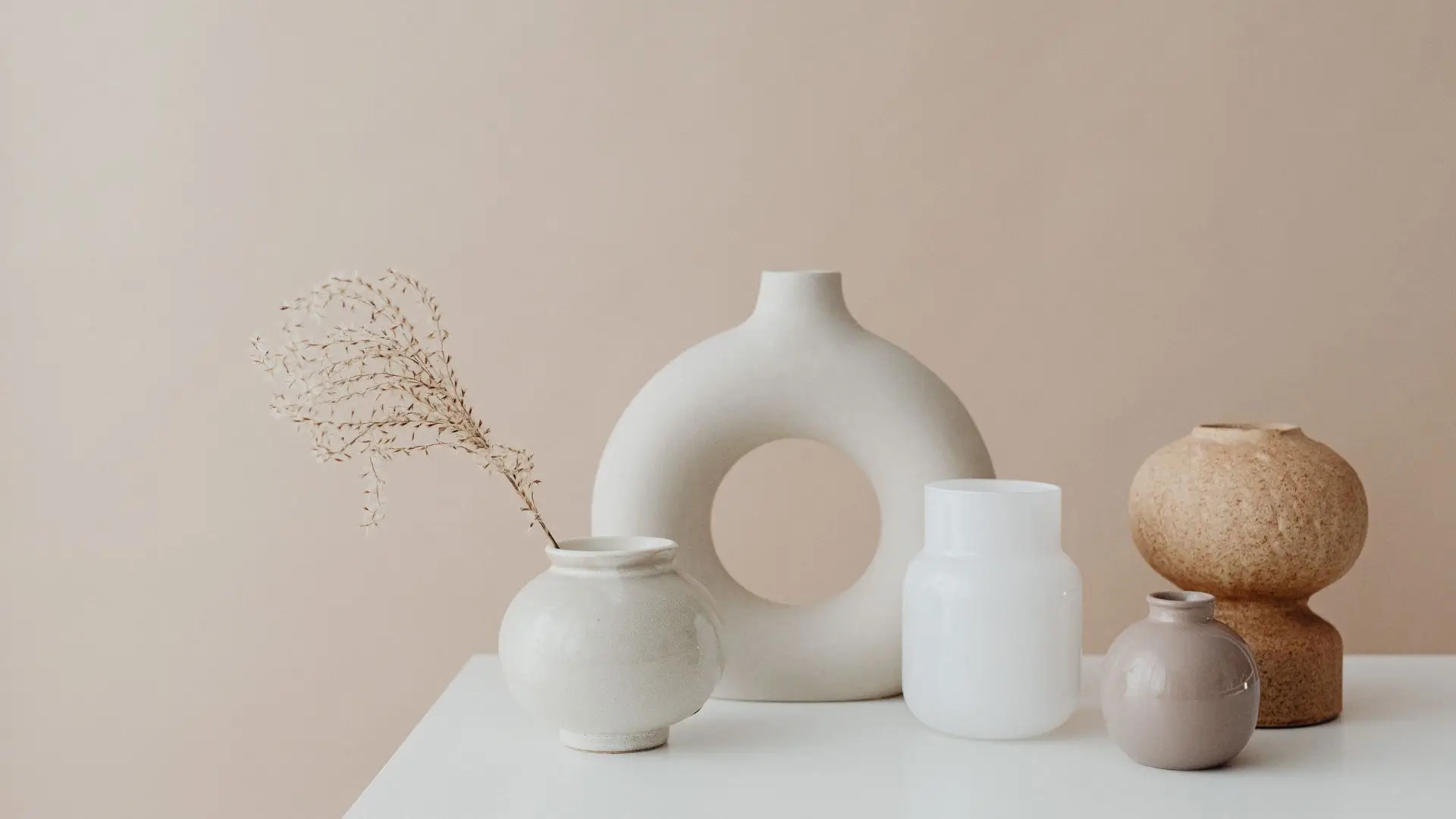 A white table adorned with multiple vases, showcasing a variety of shapes and sizes, creating an elegant display.