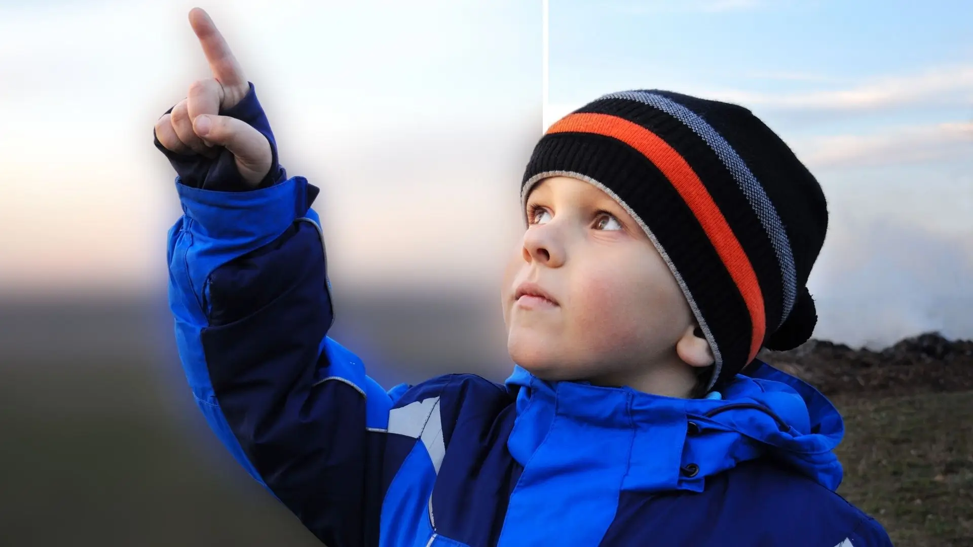 A young boy excitedly points at something in the sky, capturing a moment of wonder and curiosity.