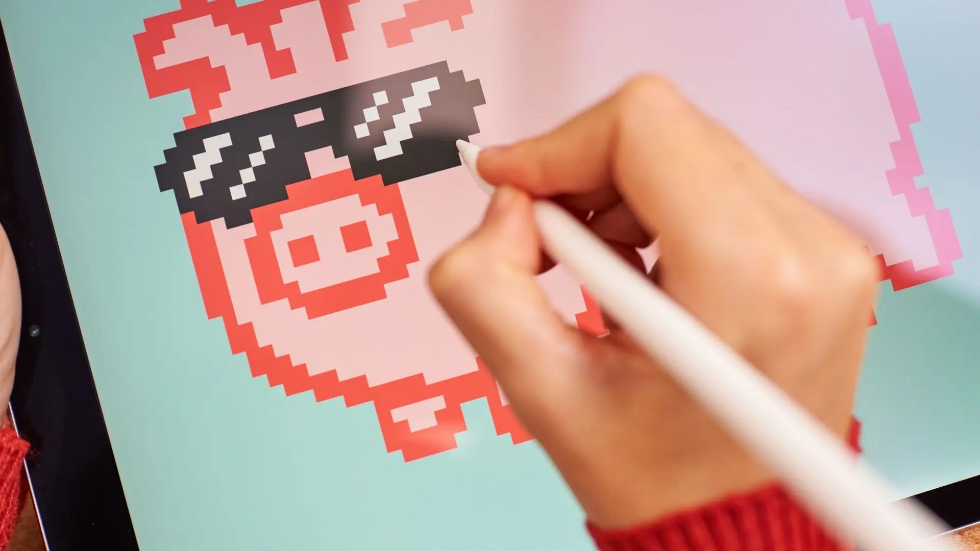 A person creating a pixel art pig on a tablet, showcasing their artistic skills and creativity.