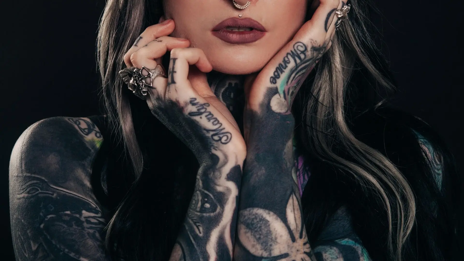 A woman showcasing her tattooed arms, displaying intricate designs and vibrant colors.