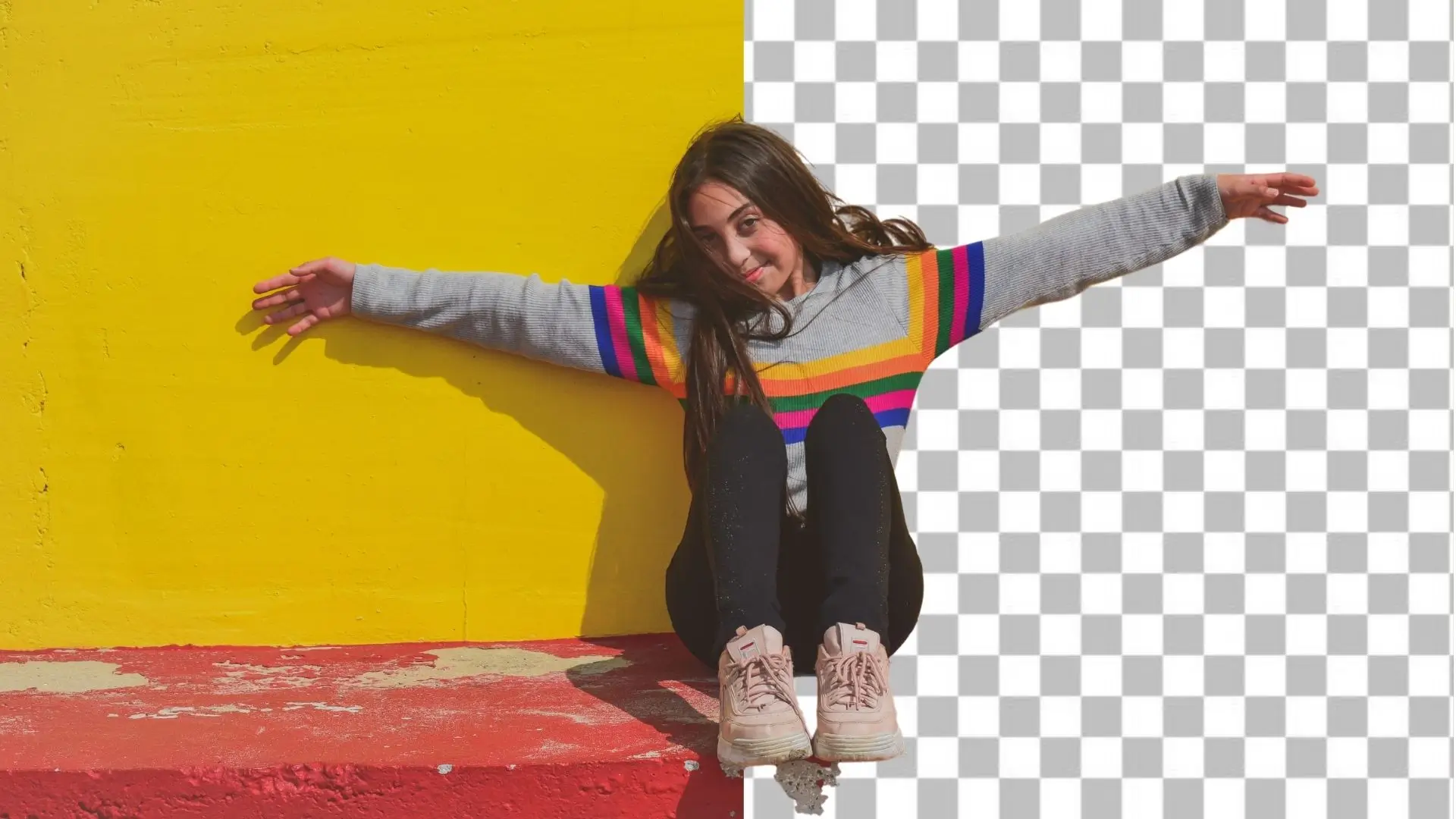 A girl sits on a wall, arms outstretched, enjoying the view and embracing the moment with a joyful expression.