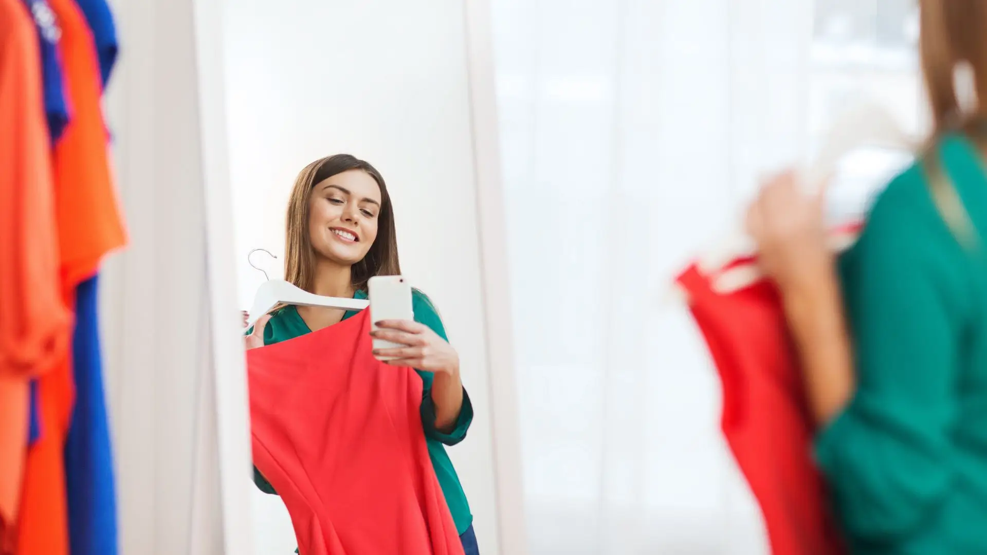 A woman admires a dress while gazing into a mirror, reflecting her thoughtful expression and style choice.