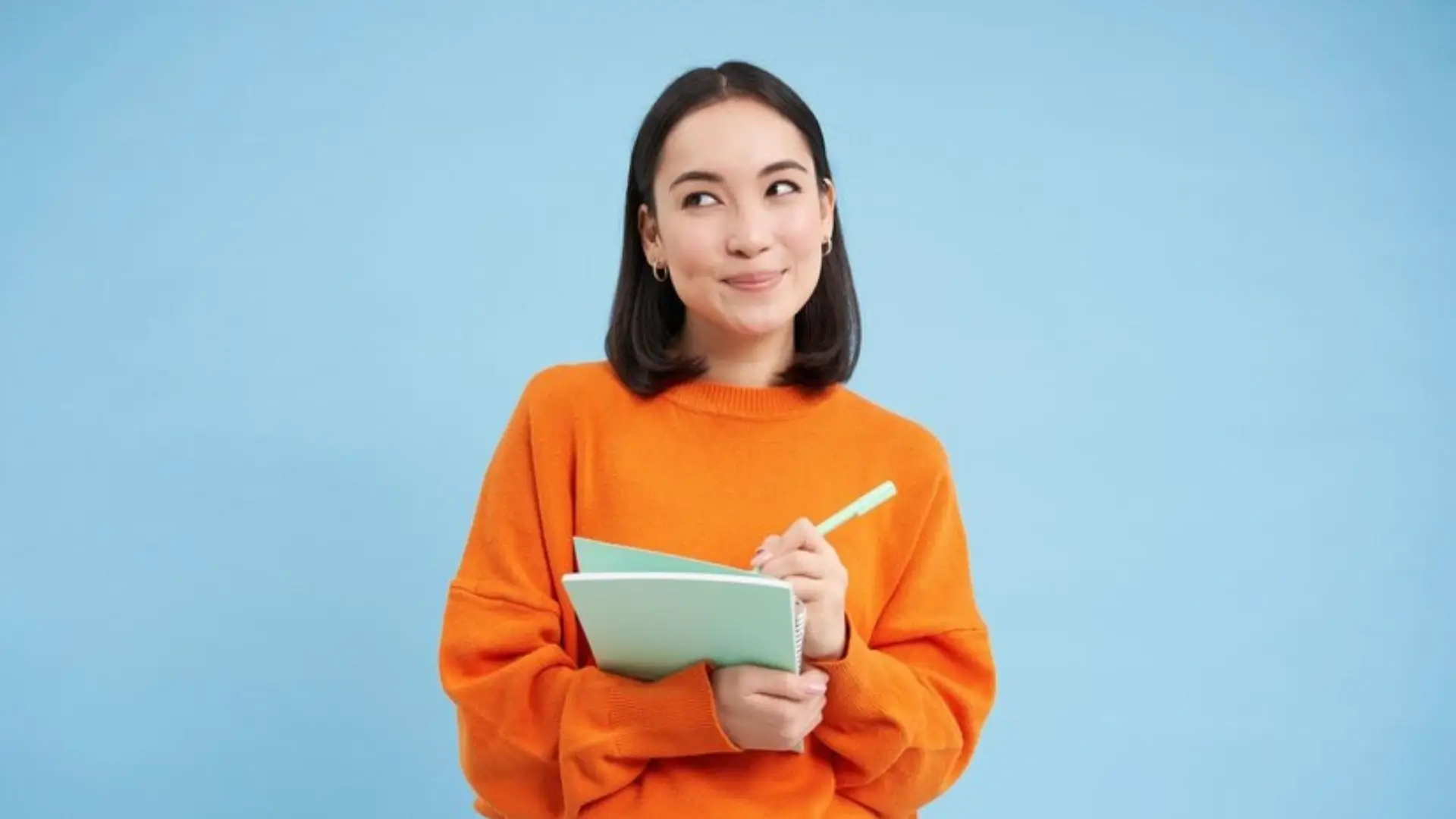 Portrait of an Asian woman holding a notebook and pen, set against a vibrant blue background.