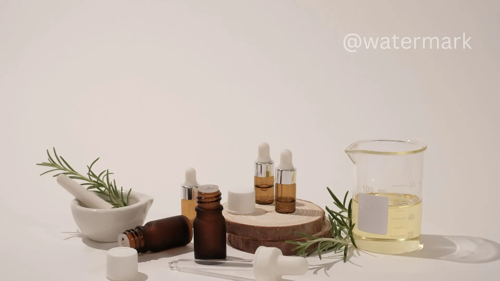 A bottle of essential oils beside a mortar and pestle, with a fresh rosemary sprig elegantly placed nearby.